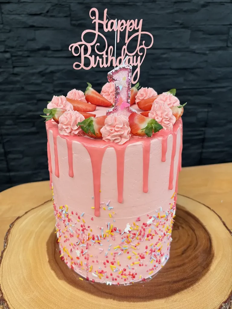 Geburtstagstorte in rosa, mit bunten Streuseln und Erdbeeren